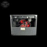 Peavey amplifier head with a black carpeted front baffle and a red bass driver visible inside, shown against a solid black background.