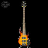 Electric bass guitar with a sunburst finish on a black background, featuring the Tone Shop logo.