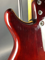 Close-up of a guitar's neck joint with a red wood finish and gold truss rod cover.