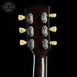 Close-up of a guitar headstock with tuning pegs on a black background, featuring 'Tone Shop' branding.