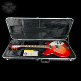 A red electric guitar displayed inside an open silver hard case with black foam lining, shown against a black background. A Tone Shop watermark is visible in the top-left corner.