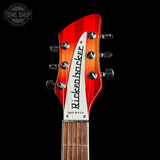 Close-up of the headstock of a Ricken ractor electric guitar against a solid black background, showing the red and orange sunburst finish, white headstock plate with black lettering, and tuning pegs.