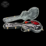 An open black guitar hard case on a black background, showing a red electric guitar inside. A Tone Shop logo watermark is visible in the top-left corner.