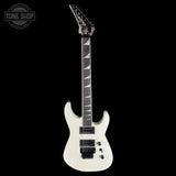 White electric guitar with a black pickguard on a black background, featuring the Tone Shop logo.