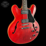 A red electric guitar with a black pickguard and chrome hardware, shown against a solid black background with a Tone Shop watermark in the top left corner.