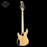 Electric bass guitar with a clear finish on a black background, featuring the Tone Shop logo.