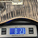 Close-up of an electric guitar body resting on a digital scale, showing the scale reading 8.23 oz.