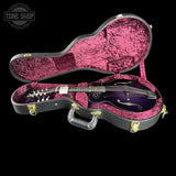 A purple mandolin in an open black hard case with a pink velvet interior, photographed on a black background. A Tone Shop watermark is visible in the upper left corner.