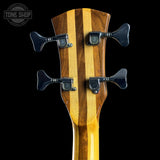 Close-up of a wooden guitar neck with tuning pegs on a black background, featuring the Tone Shop logo.