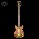 Wooden electric bass guitar on a black background with 'Tone Shop' logo.