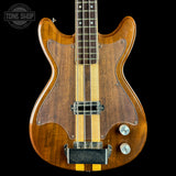 Wooden electric bass guitar with a visible brand logo in the corner.