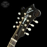 Close-up of the headstock of a Gibson electric guitar against a black background, showing the Gibson logo, tuning pegs, and strings.