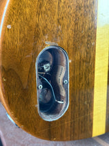 Close-up of a wooden surface with a metal component inside an oval opening.