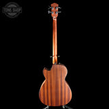 Wooden acoustic guitar on a stand with 'Tone Shop' logo in the corner.