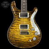 A close-up of an electric guitar body with a bright yellow-orange flamed maple wood finish, featuring a white pickguard, chrome hardware, and part of the dark fretboard. A Tone Shop watermark is visible in the top-left corner.