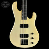 White bass guitar with black pickups on a black background, featuring 'Tone Shop' logo.