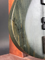 Close-up of a wooden surface with a circular cutout, possibly from a guitar or similar instrument.