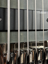 Close-up of a guitar's tuning pegs and strings with a visible brand logo.
