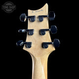 Close-up of a guitar headstock with tuning pegs on a black background, featuring the Tone Shop logo.