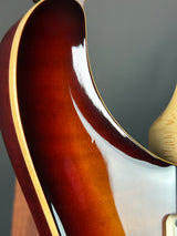 Close-up of a guitar's neck and headstock with a dark brown finish.
