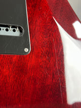 Close-up of a red guitar with visible wear and a metal pickguard.