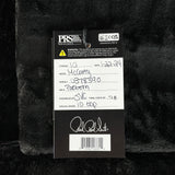 Back of a guitar with a label containing model details and serial number on a textured black background