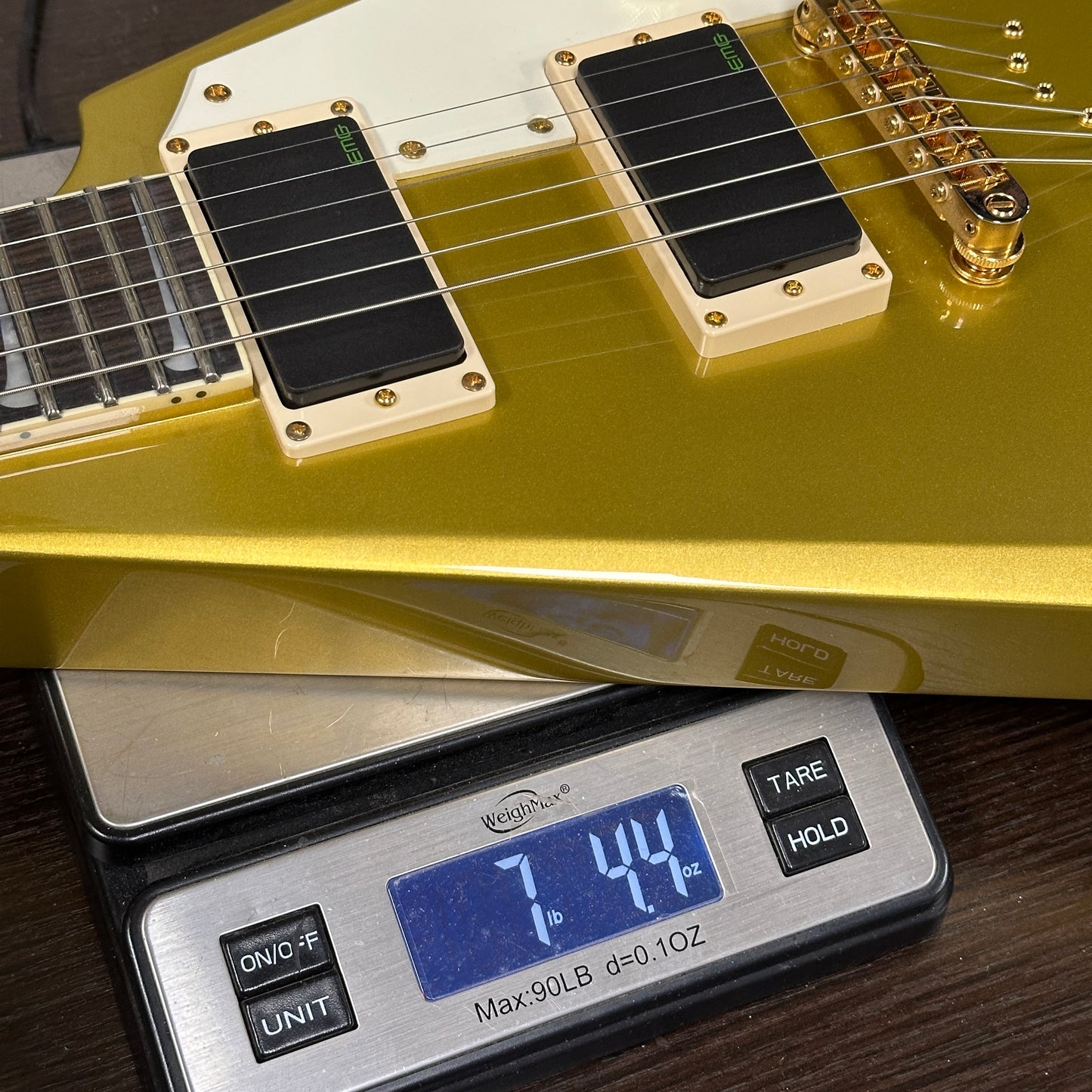 Gold electric guitar on a digital scale displaying weight