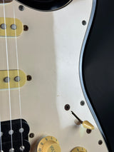 Close-up of a guitar's control knobs and strings on a white background