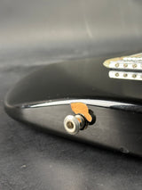 Close-up of a guitar's headstock with tuning pegs on a dark background