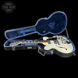 White guitar in a blue case with 'Tone Shop' logo in the corner.