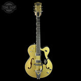 Gold electric guitar with a black background, featuring the Tone Shop logo.