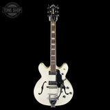 White electric guitar with a black pickguard on a black background, featuring the 'Tone Shop' logo.
