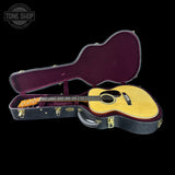Acoustic guitar in an open case with 'Tone Shop' logo in the corner.