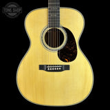 Acoustic guitar with a visible brand logo on a black background