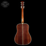 Back view of a wooden acoustic guitar on a black background with 'Tone Shop' logo.