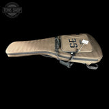 A canvas guitar or instrument gig bag in a tan color, featuring a front zippered pocket with 'SE' printed on it, shown against a solid black background.