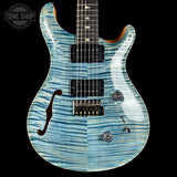 Blue electric guitar with a black pickguard on a black background, featuring the Tone Shop logo.