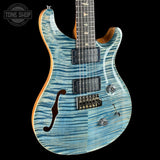 Blue electric guitar with a wavy pattern on a black background, featuring the Tone Shop logo.