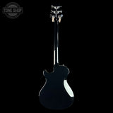 A glossy black electric guitar shown from the back against a solid black background, with a Tone Shop watermark in the upper left corner.