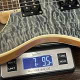 Close-up of a guitar body resting on a digital scale showing a weight reading of 7.95 lbs, with part of the neck and pickups visible.