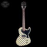 A double-cutaway electric guitar with a cream-colored body covered in black polka dots, a black pickguard, and a dark brown neck, shown against a solid black background. A 'TONE SHOP' watermark is visible in the top-left corner.