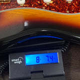 Used 2006 Fender Deluxe Player Strat 3-Tone Sunburst on scale displaying weight.
