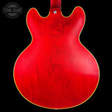 Close-up of a red electric guitar body with 'Tone Shop' logo in the corner.