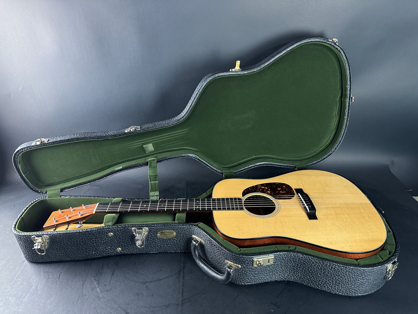 Acoustic guitar in an open case on a dark surface