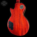 Close-up of a red electric guitar body with a visible brand logo on a black background.