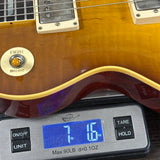 Guitar being weighed on a digital scale with a display showing weight.