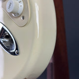 Close-up detail of a cream-colored electric guitar body, showing part of the white tone control and a chrome pickguard.