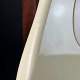 Close-up of a glossy cream-colored curved surface, likely part of a guitar body, showing minor scuffs and a light reflection.