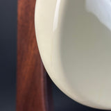 Close-up of a glossy off-white ceramic bowl or cup edge with a visible thin crack, positioned next to a dark brown wooden surface.