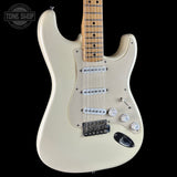 Cream-colored electric guitar with a maple neck, featuring three single-coil pickups, a black bridge, and white control knobs, shown against a solid black background.